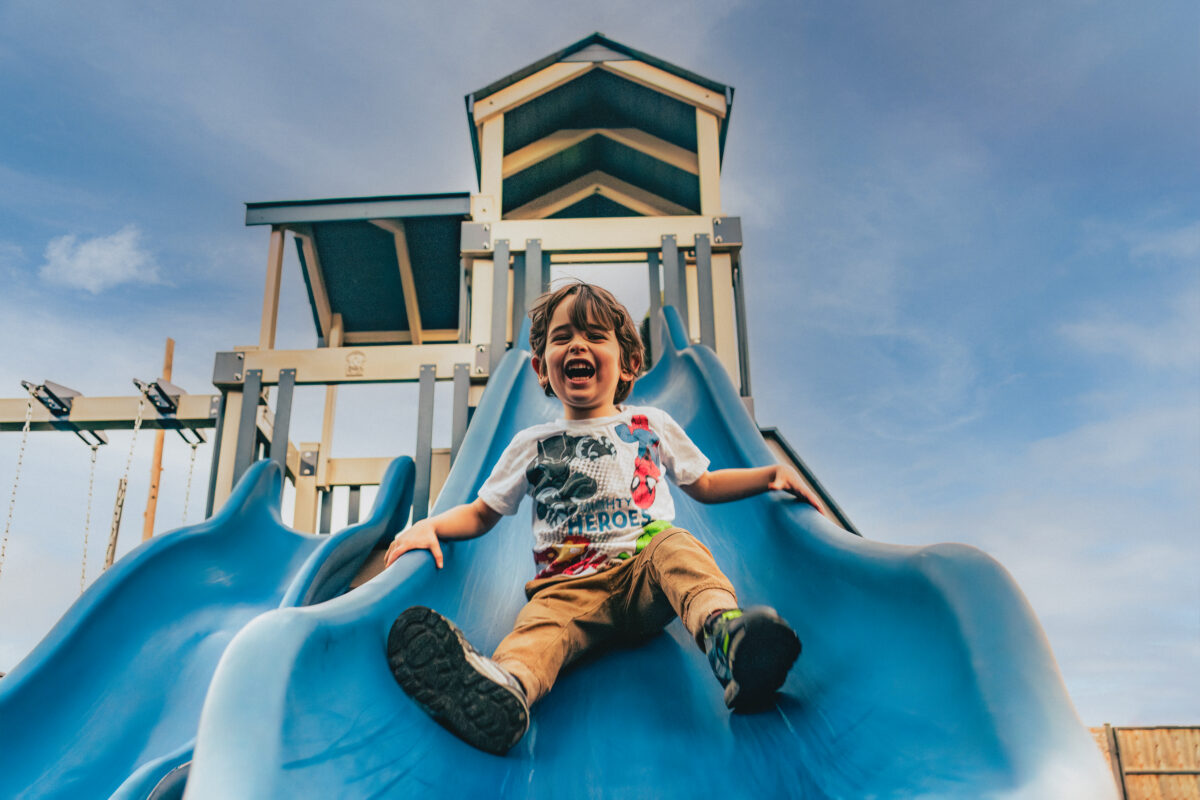 Kid sliding down slide on the playground at Wild Acre